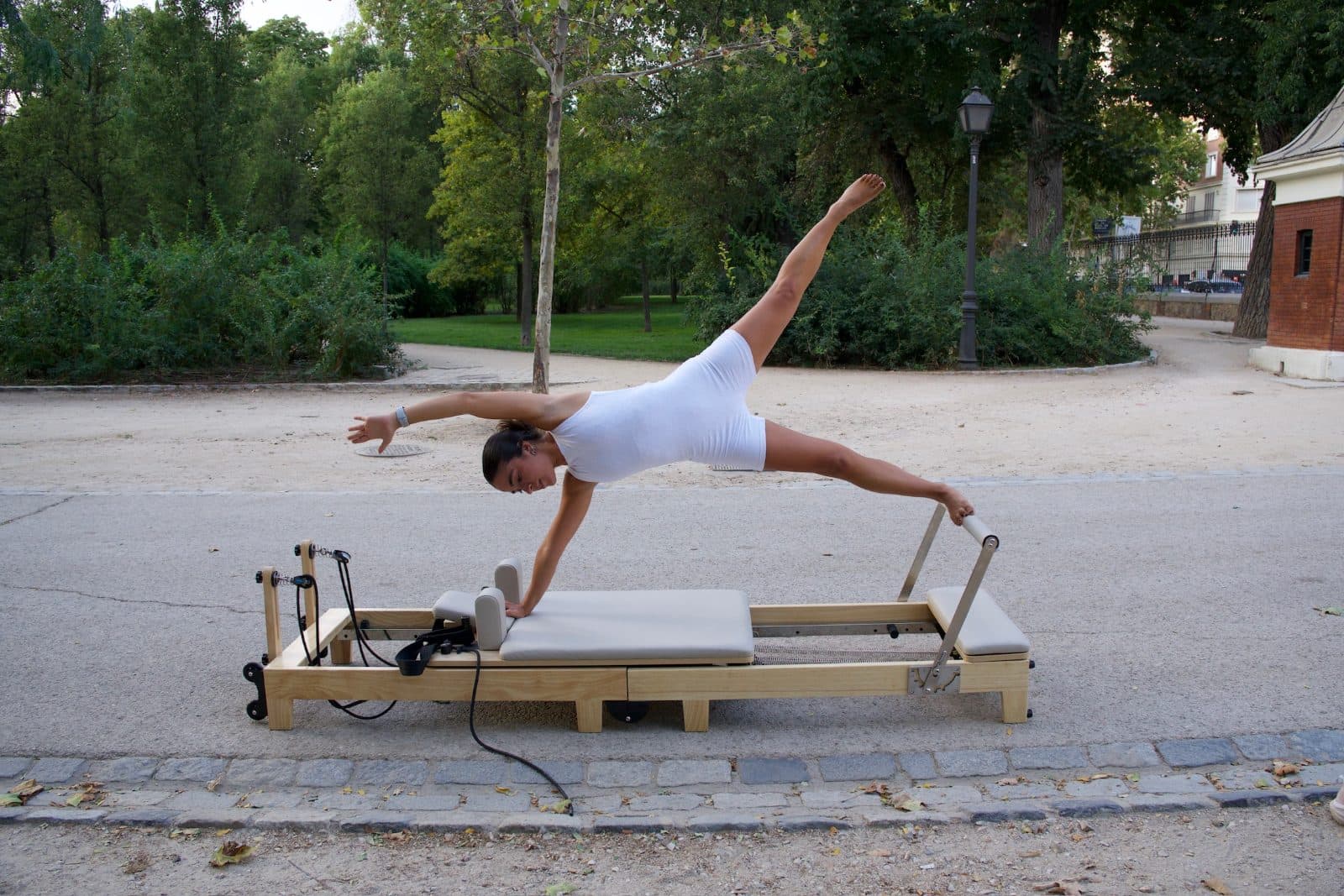 Plancha lateral con la pierna elevada sobre un reformer de Pilates