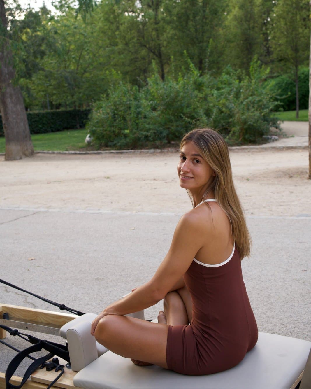 Claudia Calás, fundadora de TEMPO, sonríe sentada en el reformer en un parque
